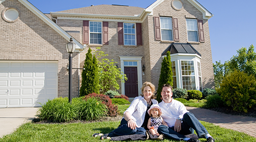 Family of three sitting at the front yard of their home - Learn more about the Insurance Products and Services we offer